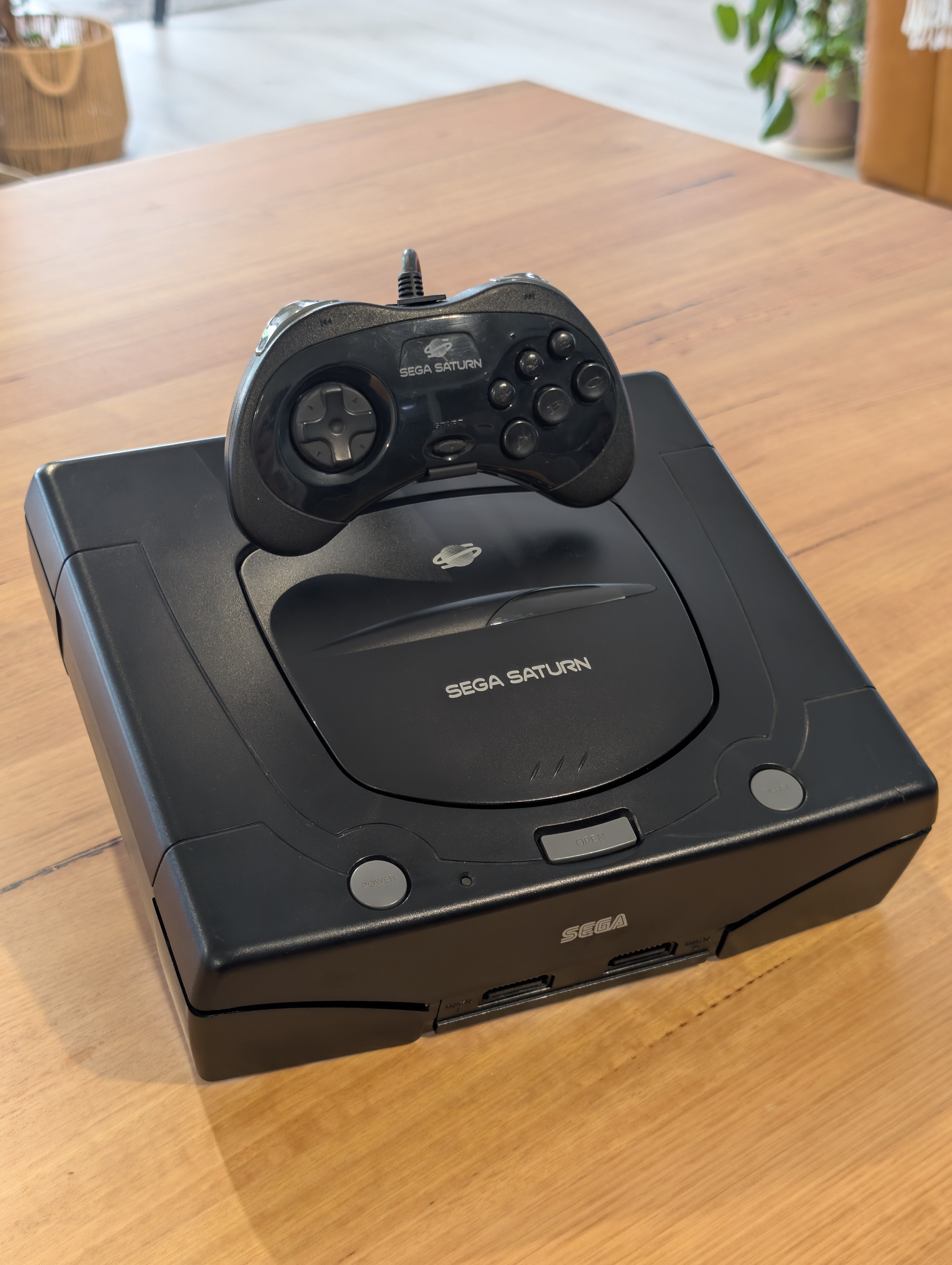 Sega Saturn konsol framifrån på ställ – retro display med kontroller