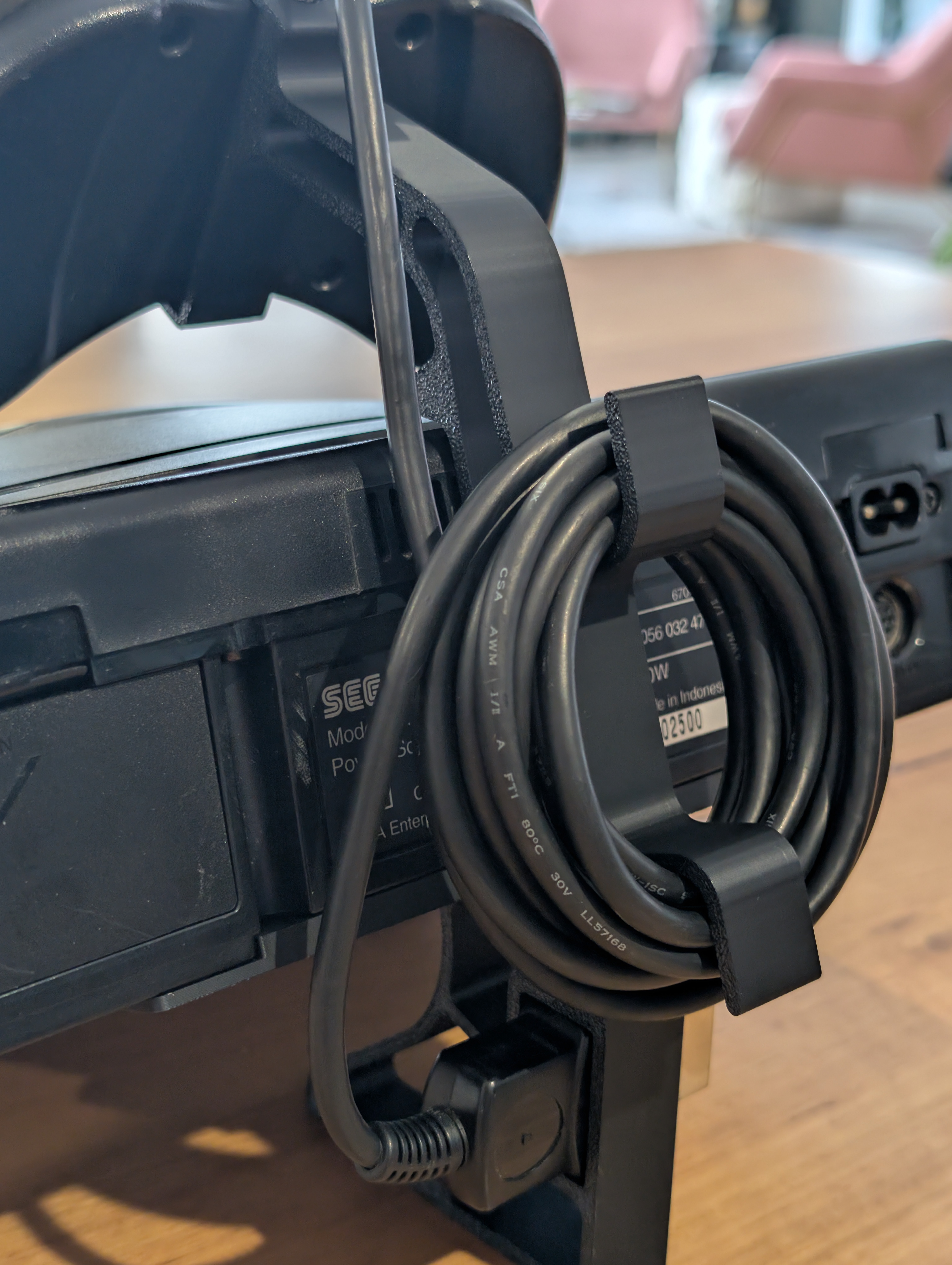 Närbild på Sega Saturn ställets kabelhållare – håller sladden ordnad